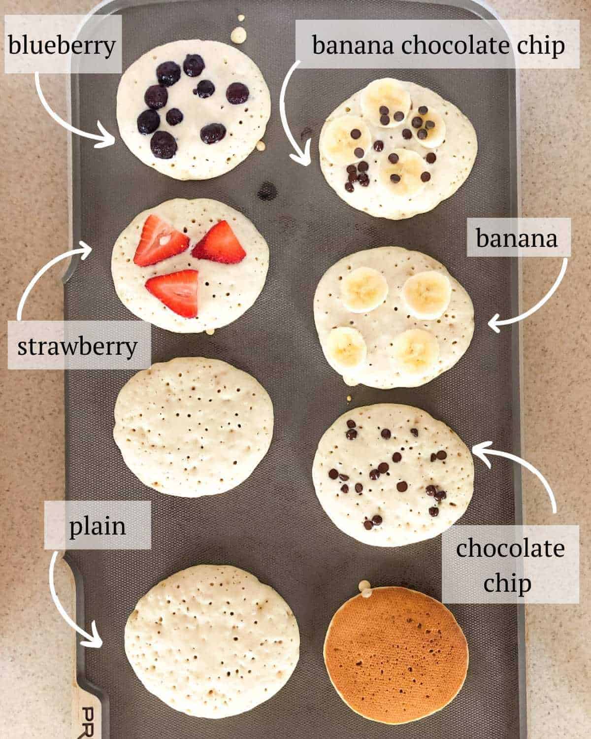 A griddle with oat milk pancakes topped with various mix ins.