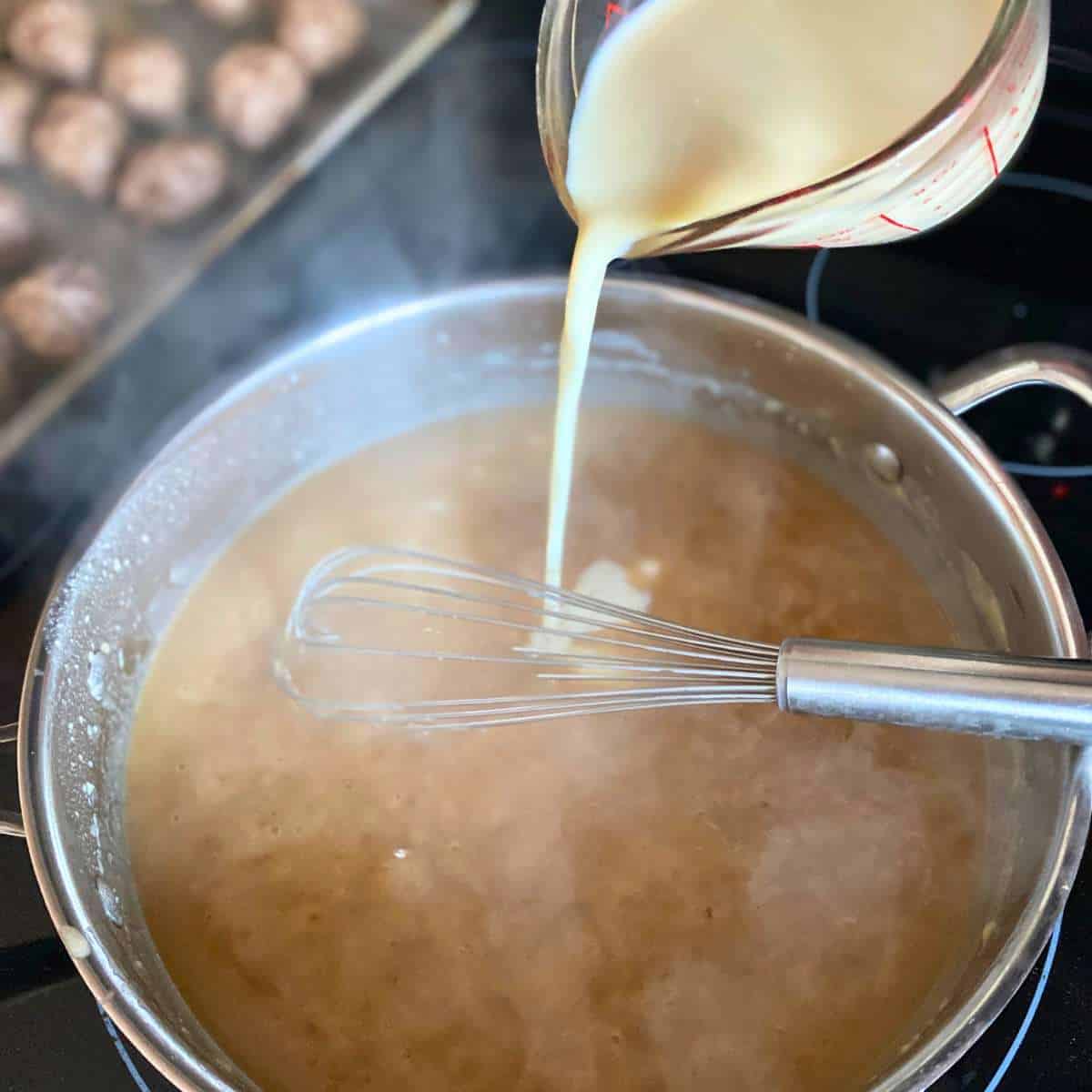 Dairy free milk being added to the meatball sauce.