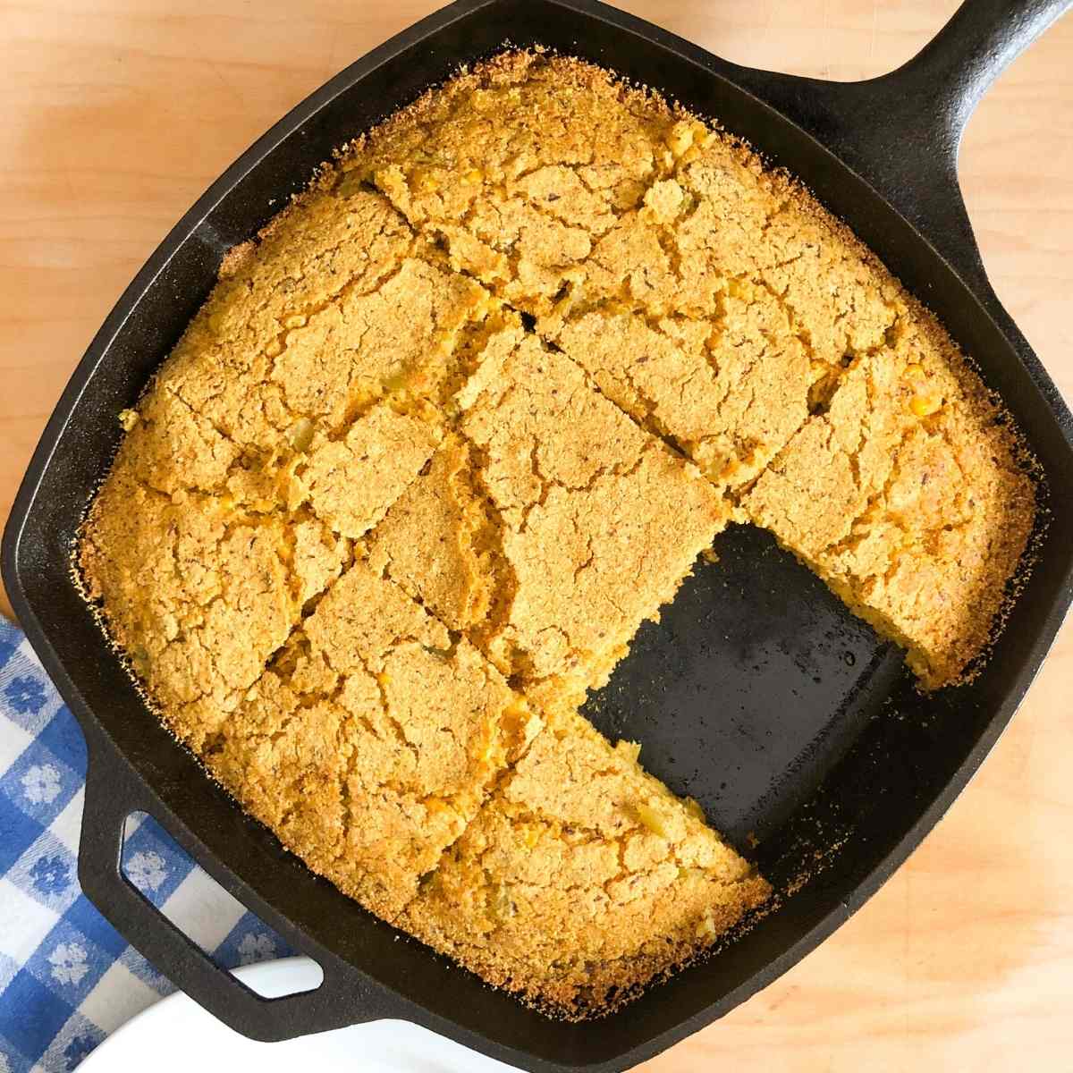 A skillet with gluten free cornbread cut into squares.