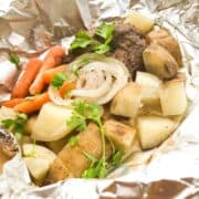 A foil packet filled with potatoes, carrots and onions.