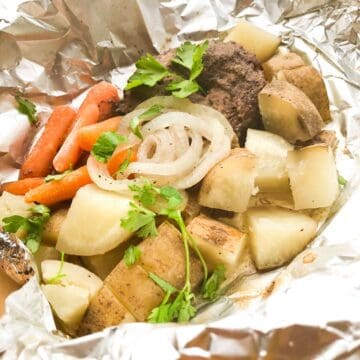 A foil packet filled with potatoes, carrots and onions.