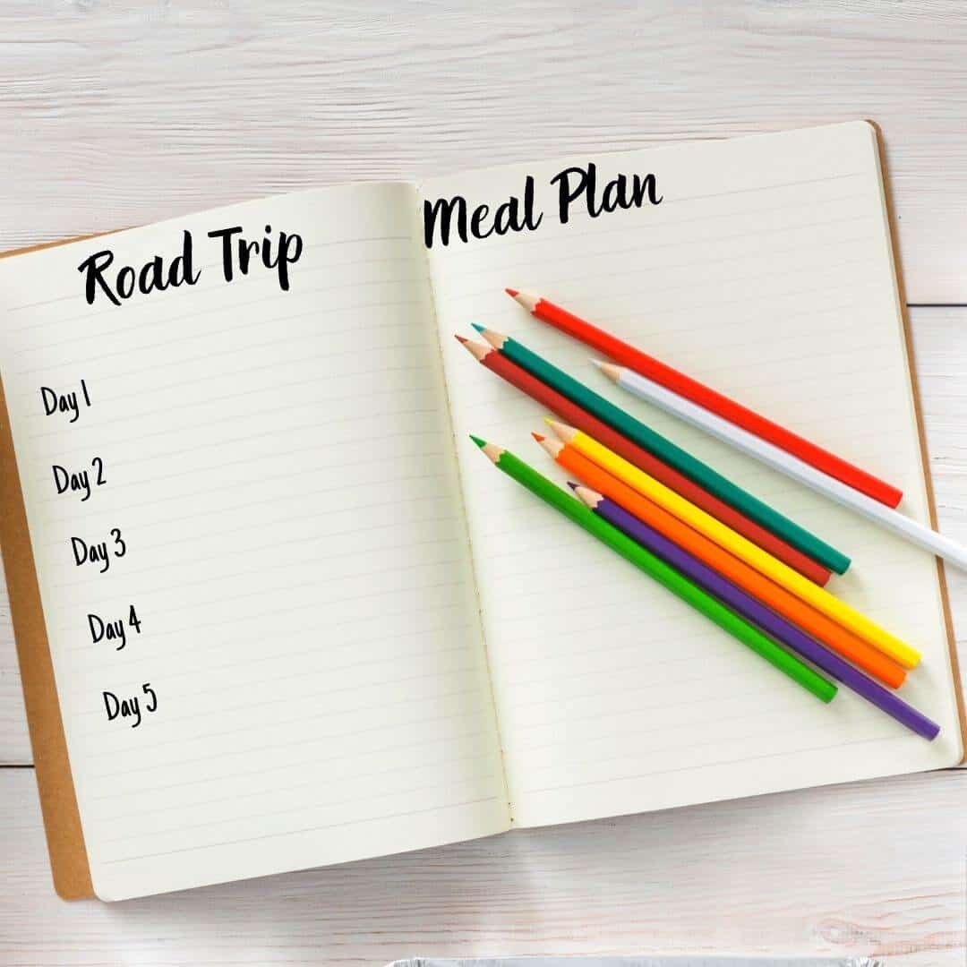 A lined journal with a road trip meal plan and colored pencils on it.